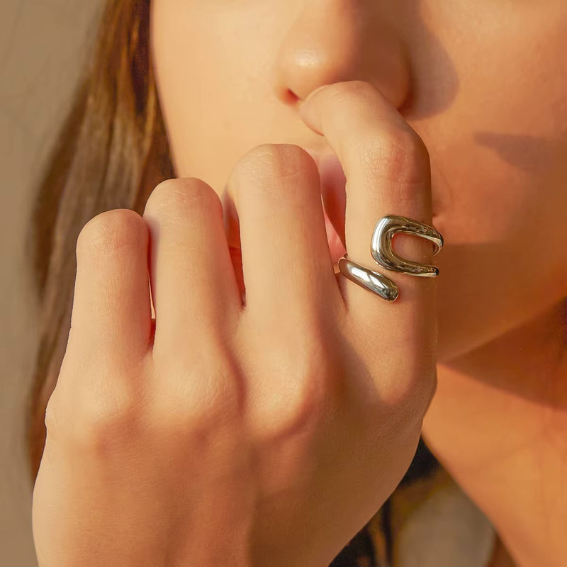 Anillo Praia de acero quirúrgico con diseño abierto y forma curva orgánica en modelo.