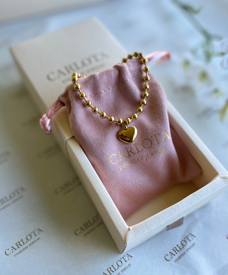 Pulsera con cuentas y dije de corazón de acero quirúrgico. Color oro en caja